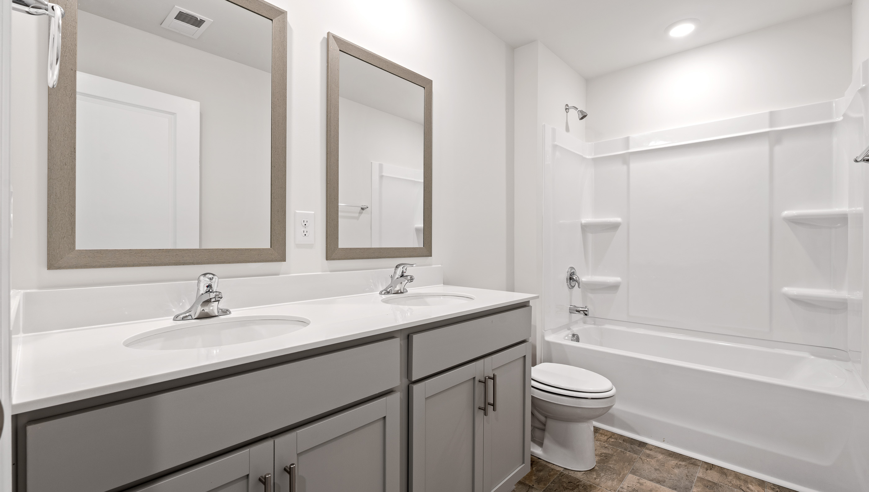 Hall bathroom with dual sink vanity and combination shower / tub.