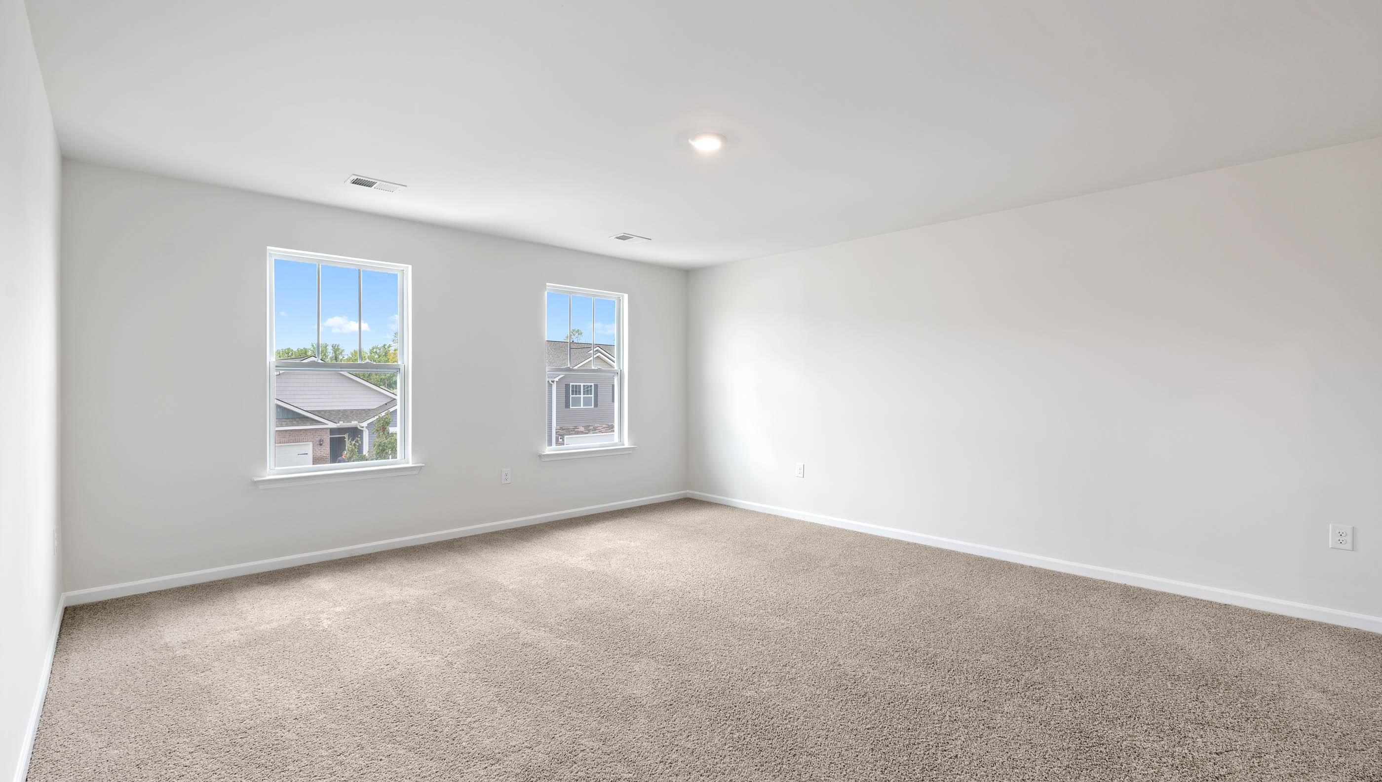 Primary bedroom with two large windows.
