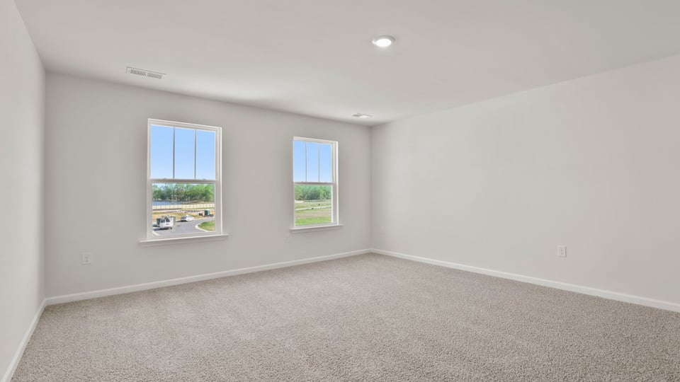 Primary bedroom with carpet and window.
