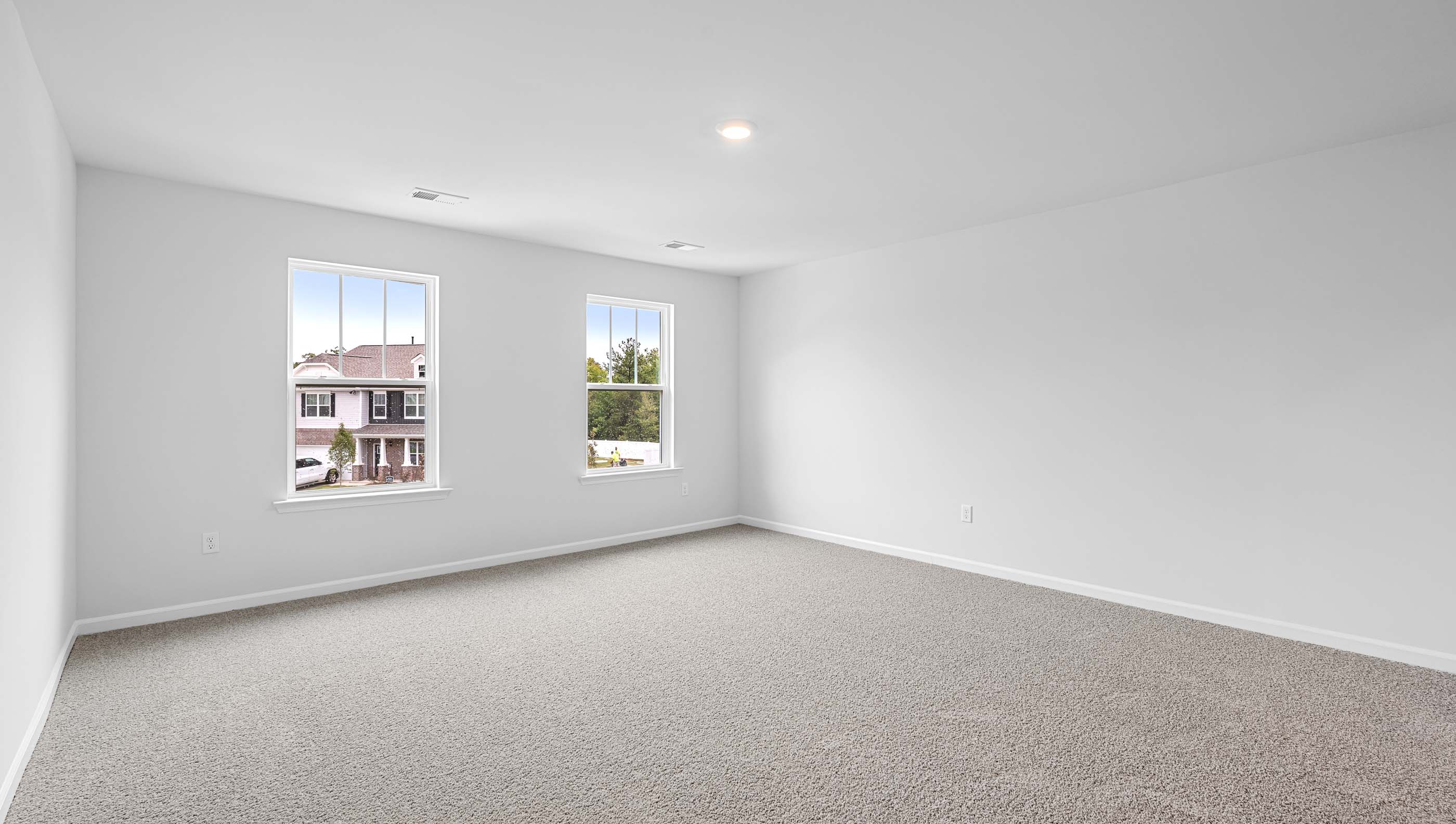 Primary bedroom with double windows and carpet.