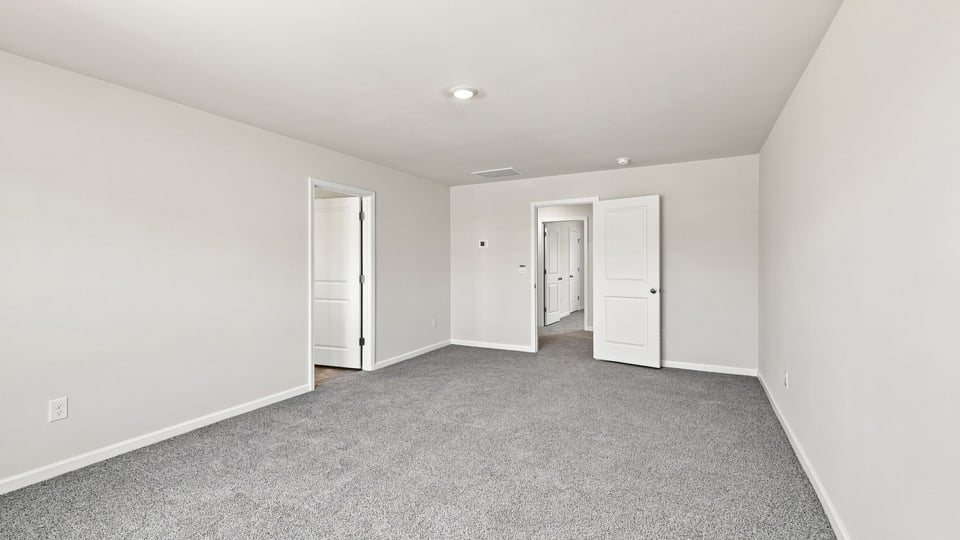 Primary bedroom with carpet and windows.