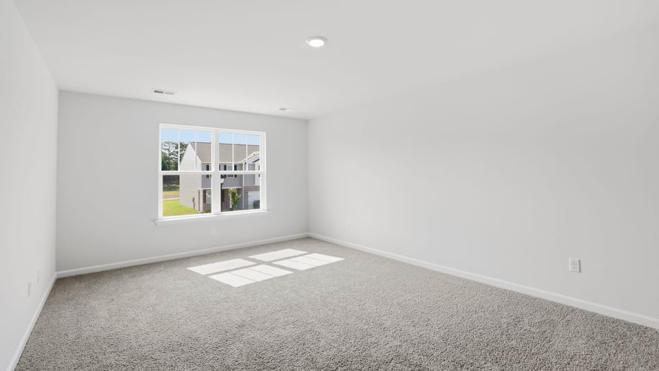 Primary bedroom with carpet and windows.
