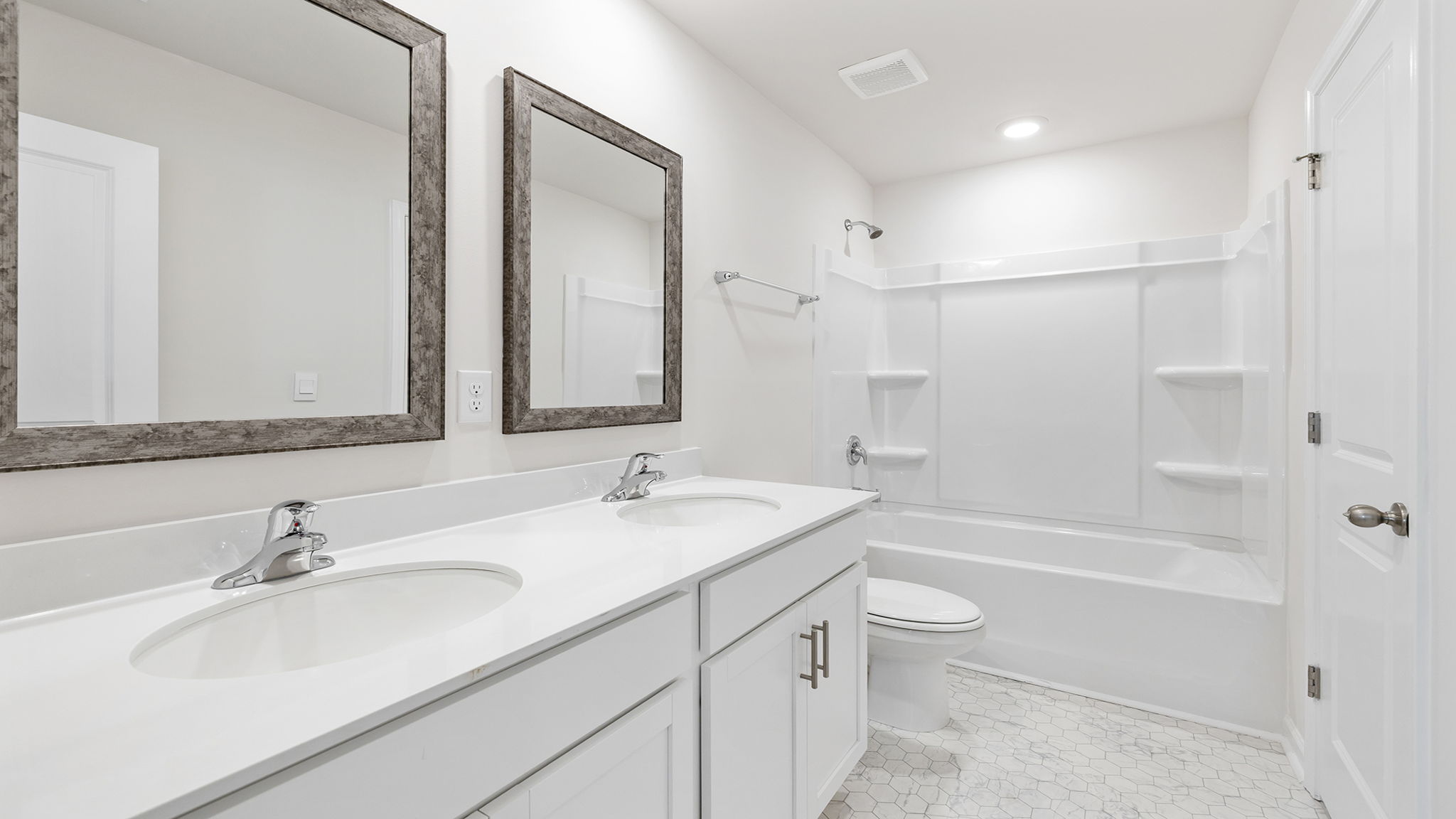 Hall bathroom with dual sink vanity and combination shower / tub.