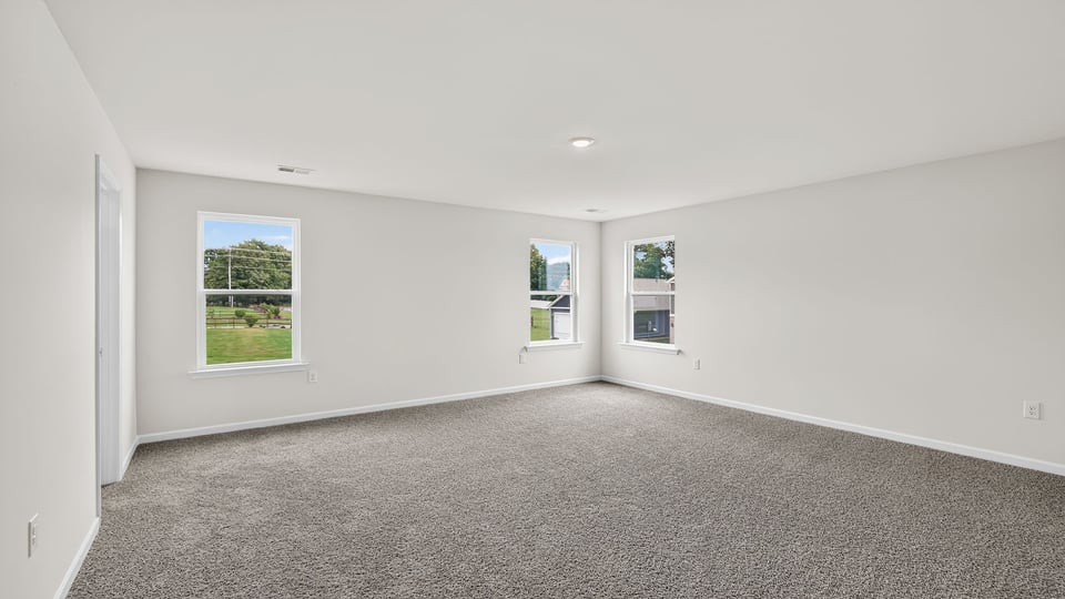 Primary bedroom with windows and carpet.