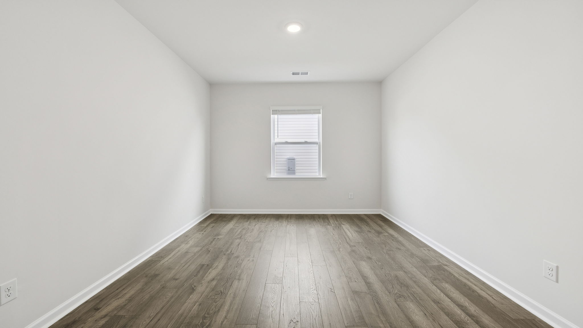 Formal dining room with window and laminate flooring.