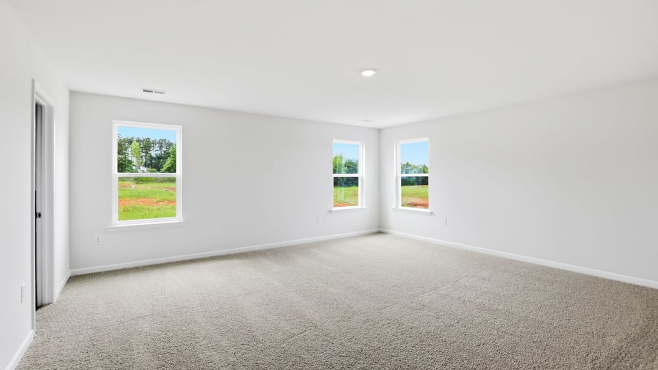 Primary bedroom with carpet and window.