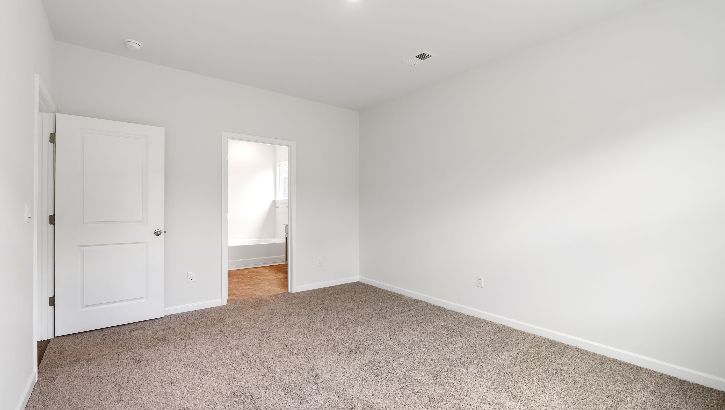 Primary bedroom with carpet and window.