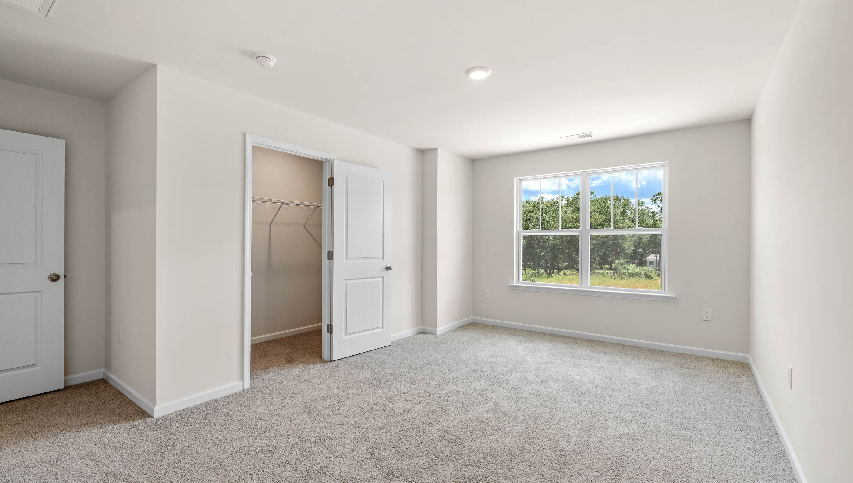 Primary bedroom with large window and carpet.