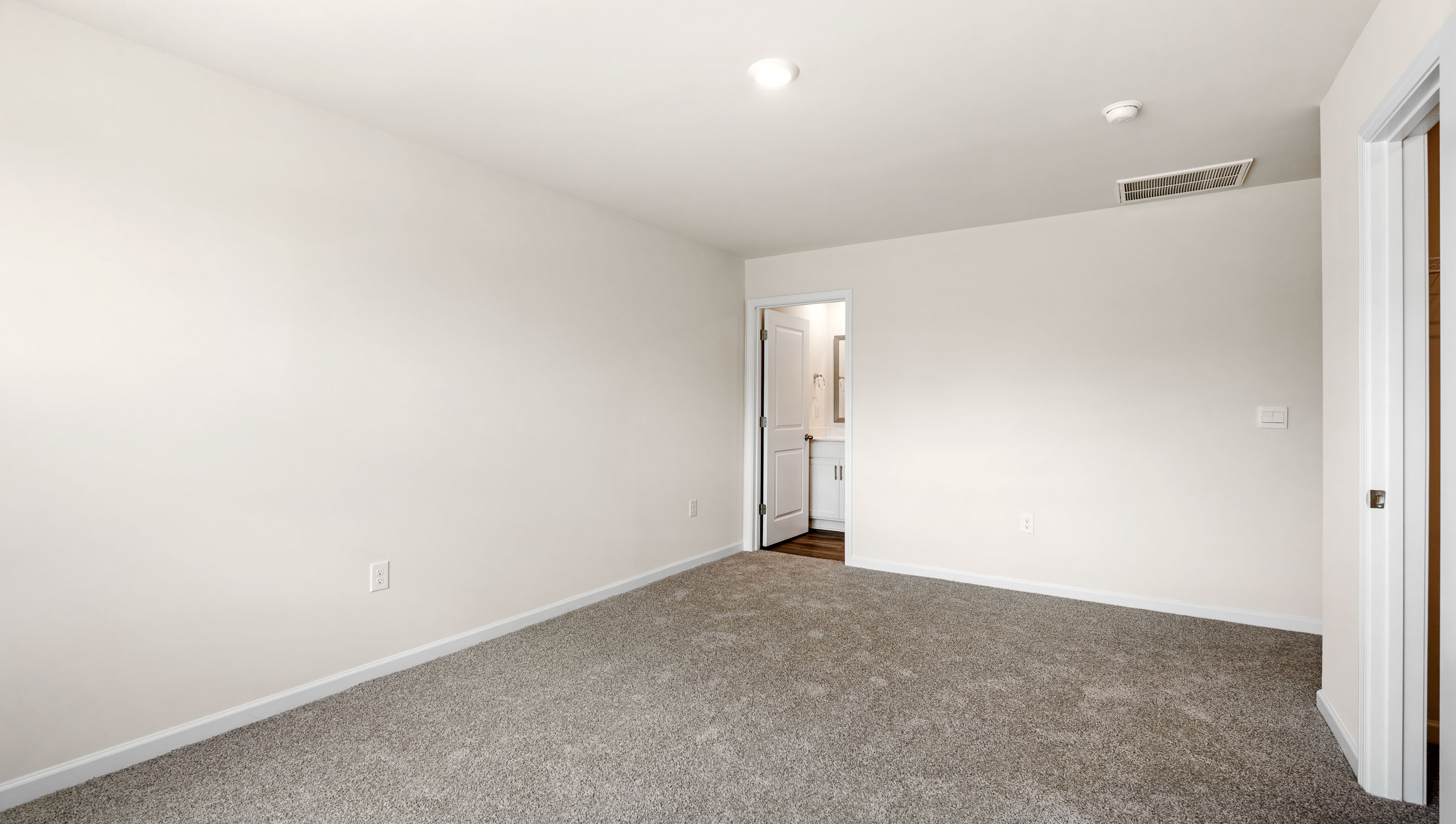 Primary bedroom with large window and carpet.