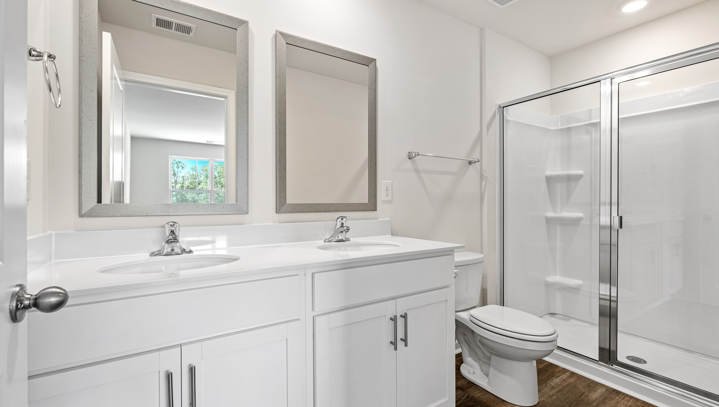 Primary bathroom with dual sink vanity and mirrors.