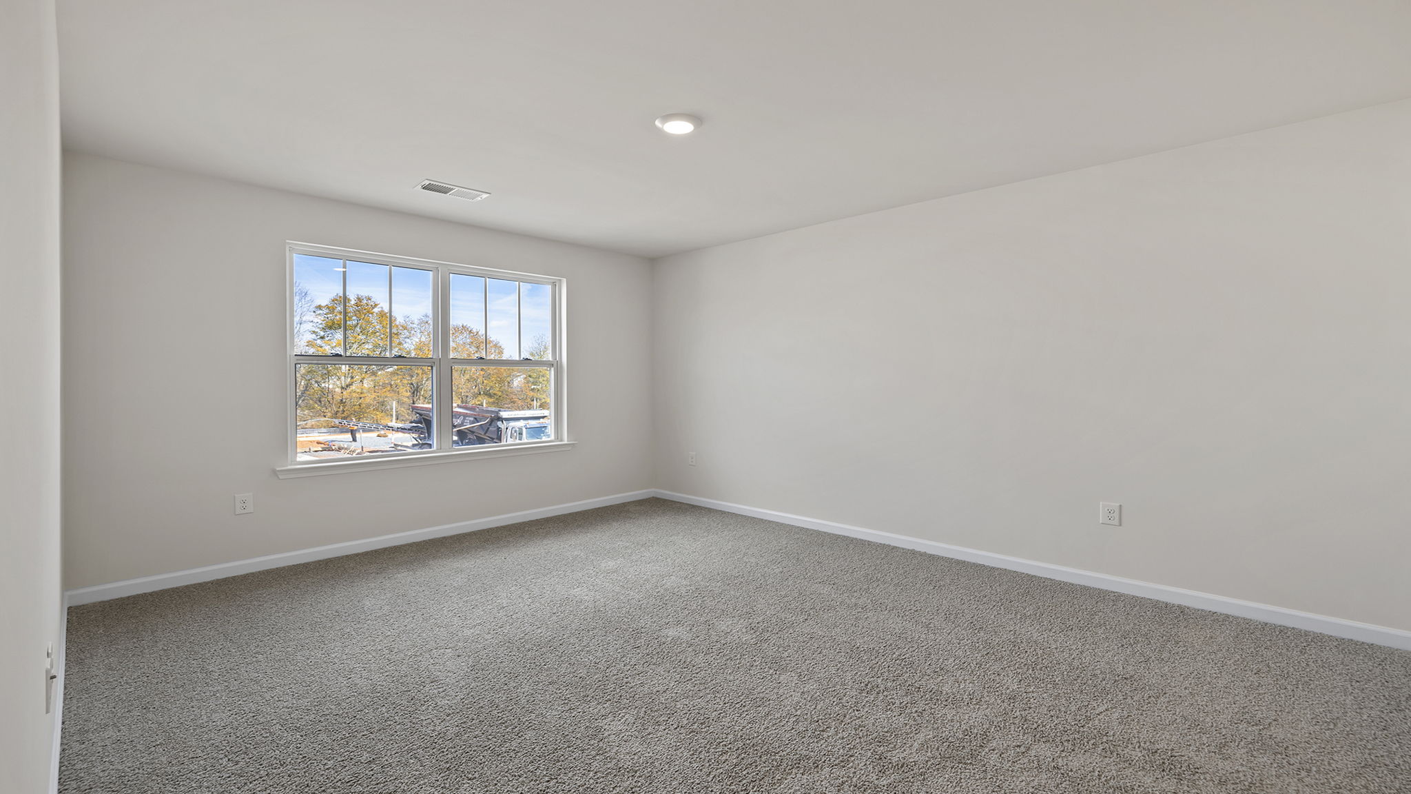 Primary bedroom with window and carpet.