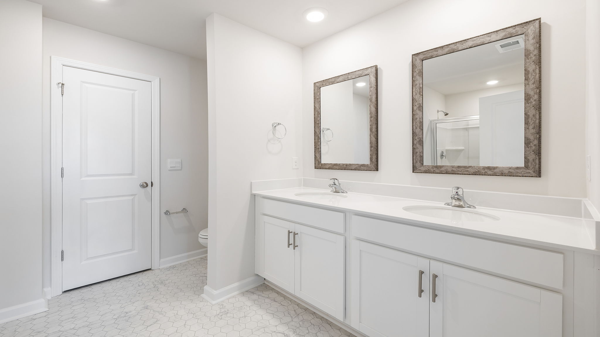 Primary bathroom with dual sink vanity and mirrors.