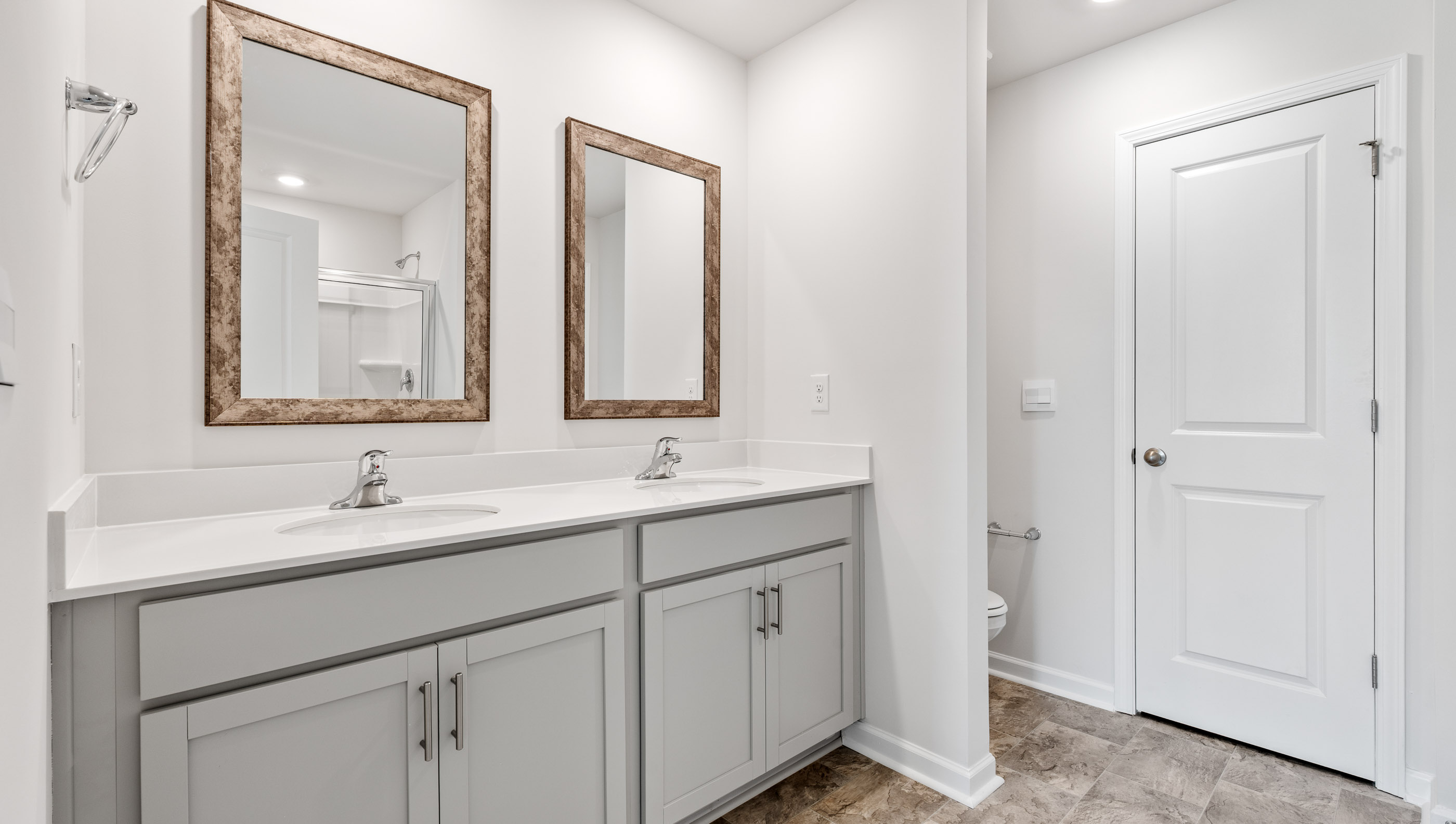Primary bathroom with dual sink vanity and mirrors.