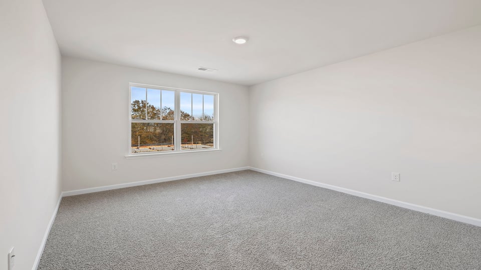 Primary bedroom with window and carpet.