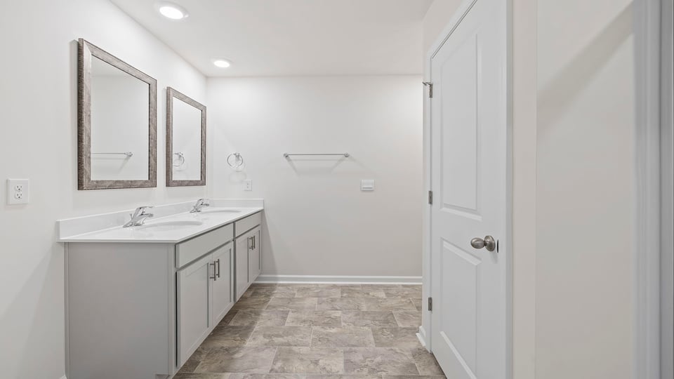 Primary bathroom with dual sink vanity and mirrors.