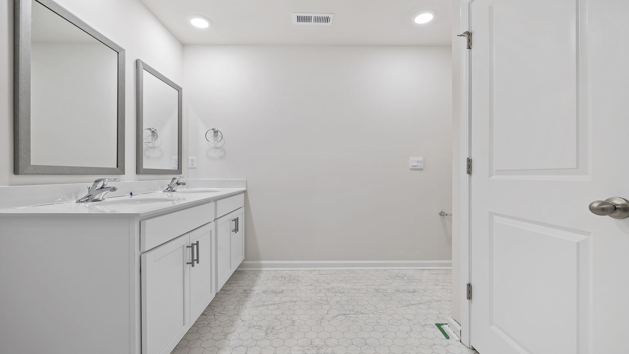 Primary bathroom with dual sink vanity and mirrors.