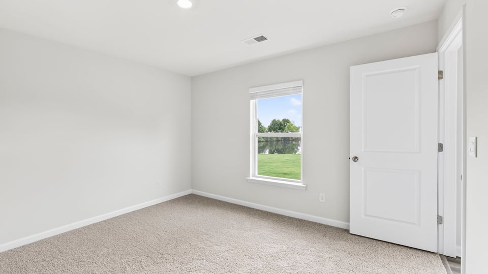Primary bedroom with carpet and windows.