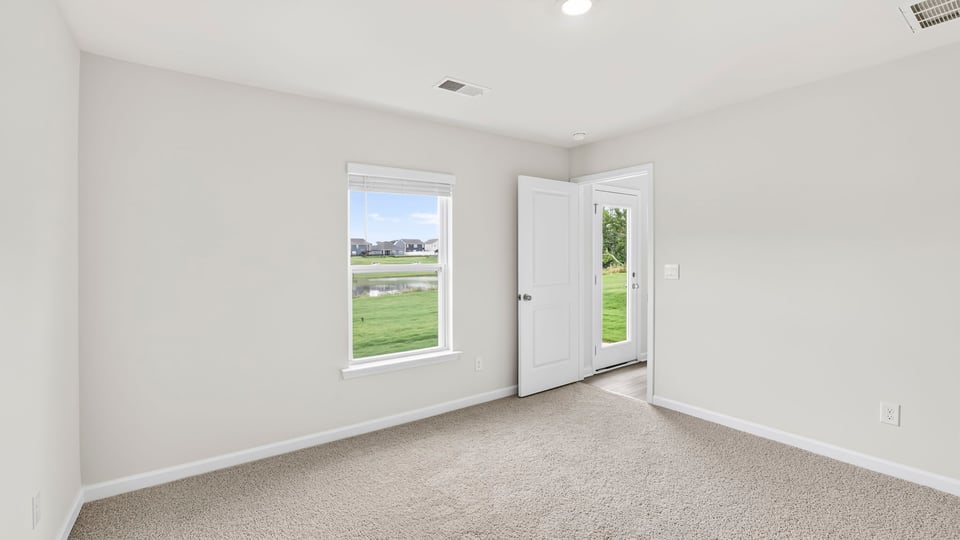 Primary bedroom with carpet and windows.