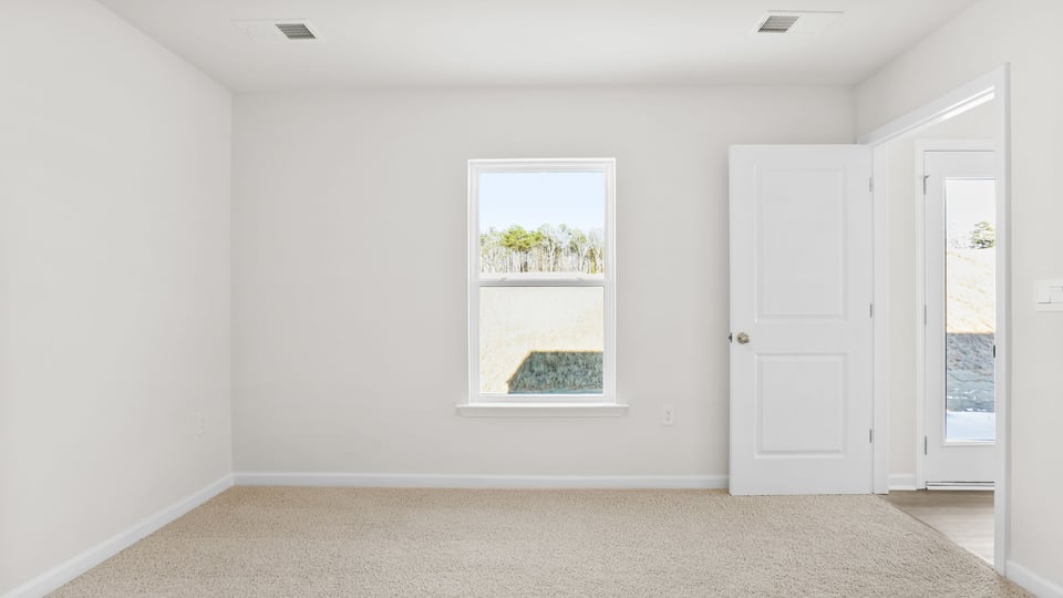 Primary bedroom with carpet and windows.