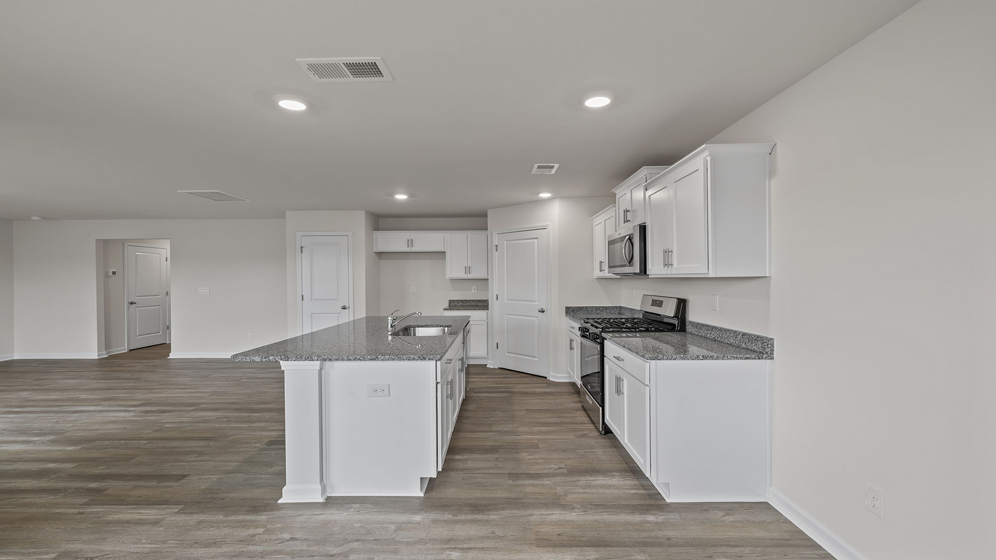 Open kitchen with recessed lighting and white cabinets.