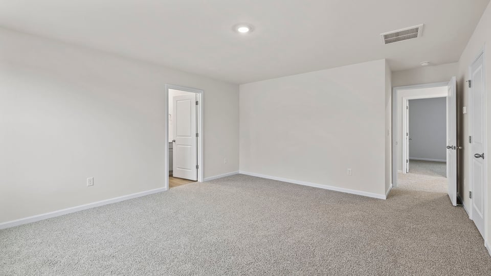 View of primary bedroom with large window and entrance into primary bath.