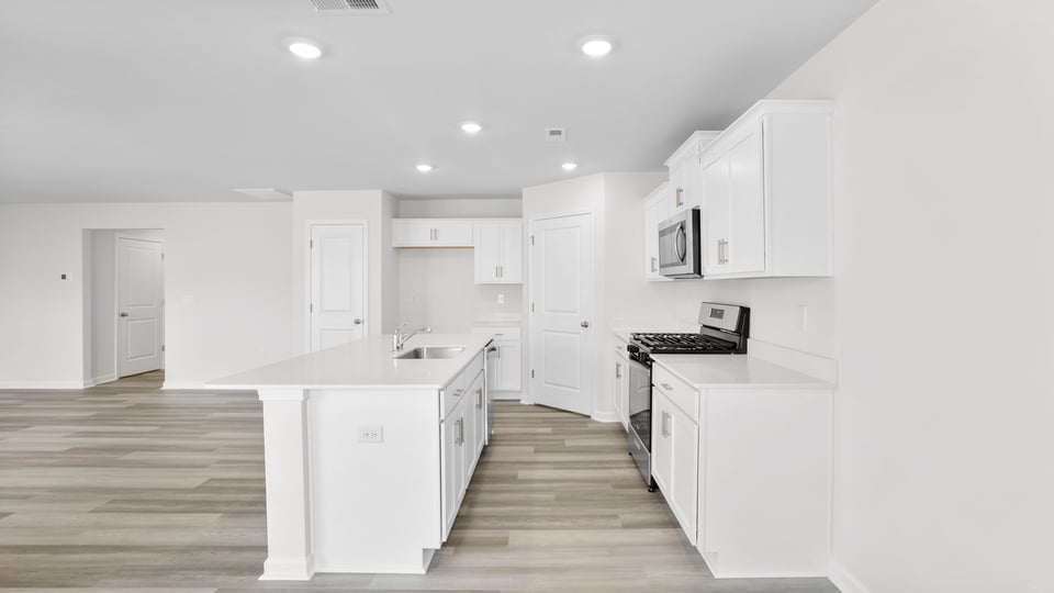 View from dining area into open floorplan showing kitchen and family room.