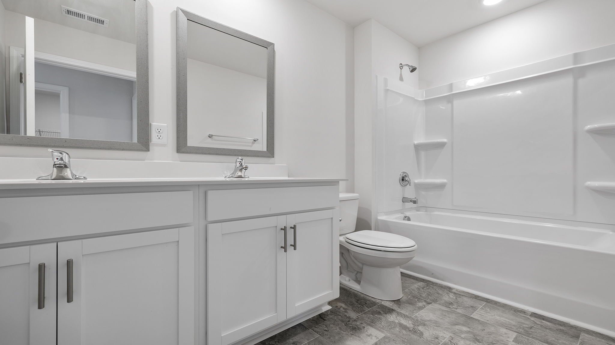 Hall bathroom with dual sink vanity and combination shower / tub.