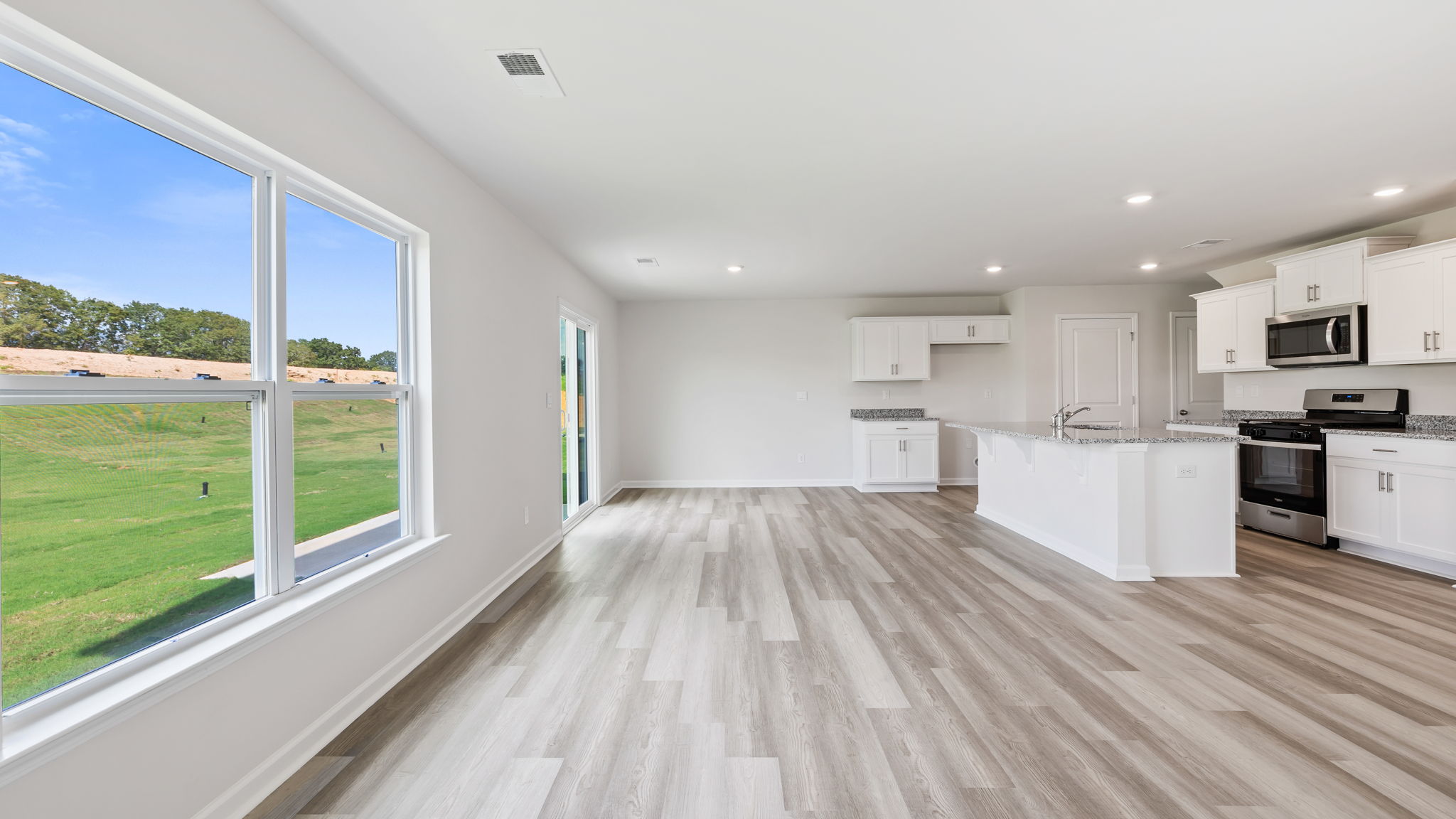 View from family room with large windows toward the kitchen and dining area.