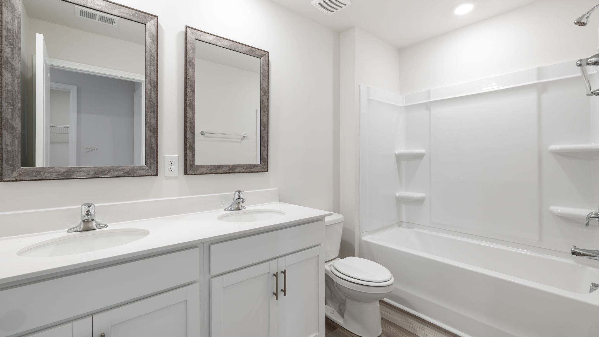 Hall bathroom with dual sink vanity and combination shower / tub.