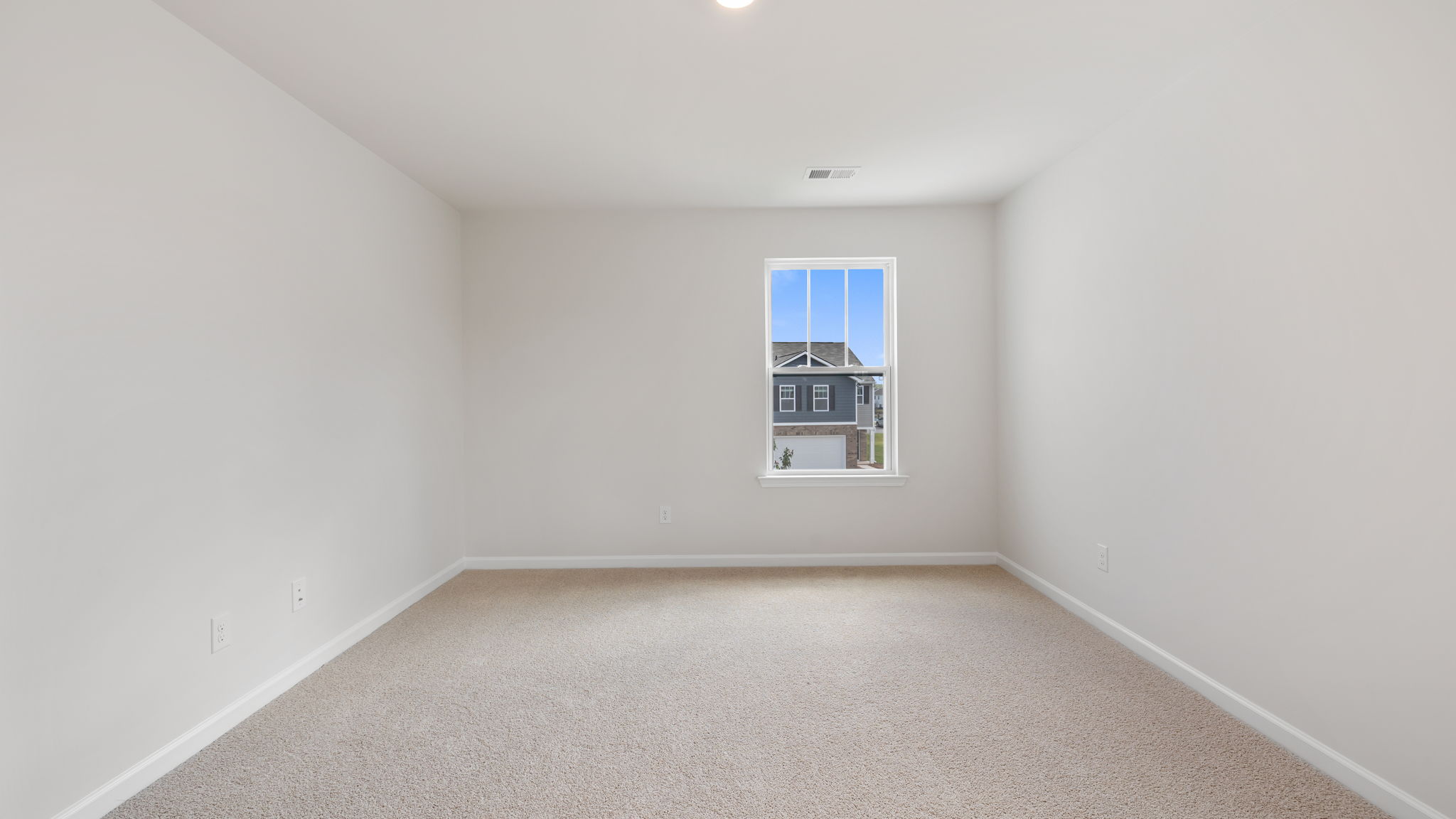 Primary bedroom with carpet and window.
