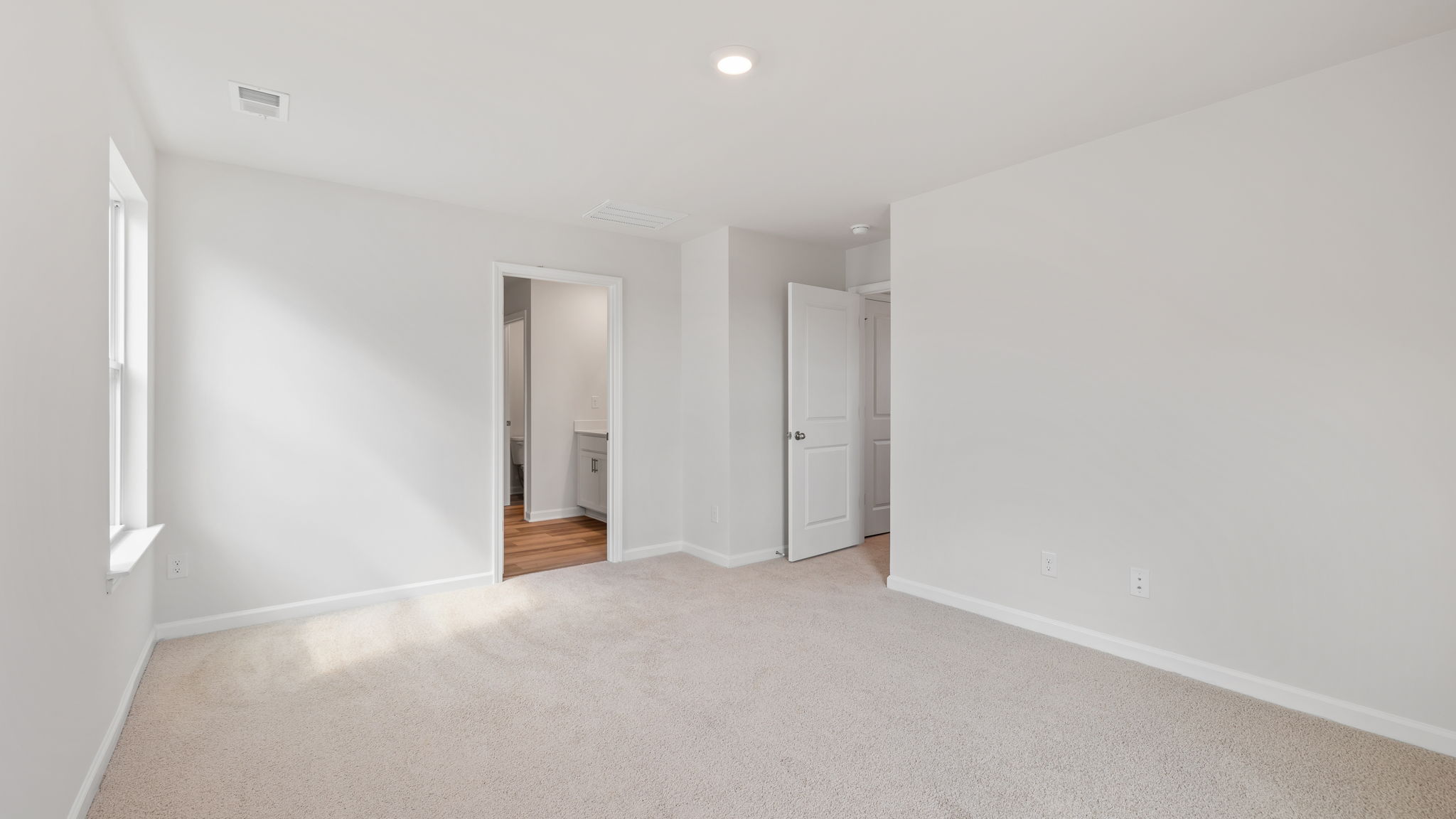 Primary bedroom with carpet and window.