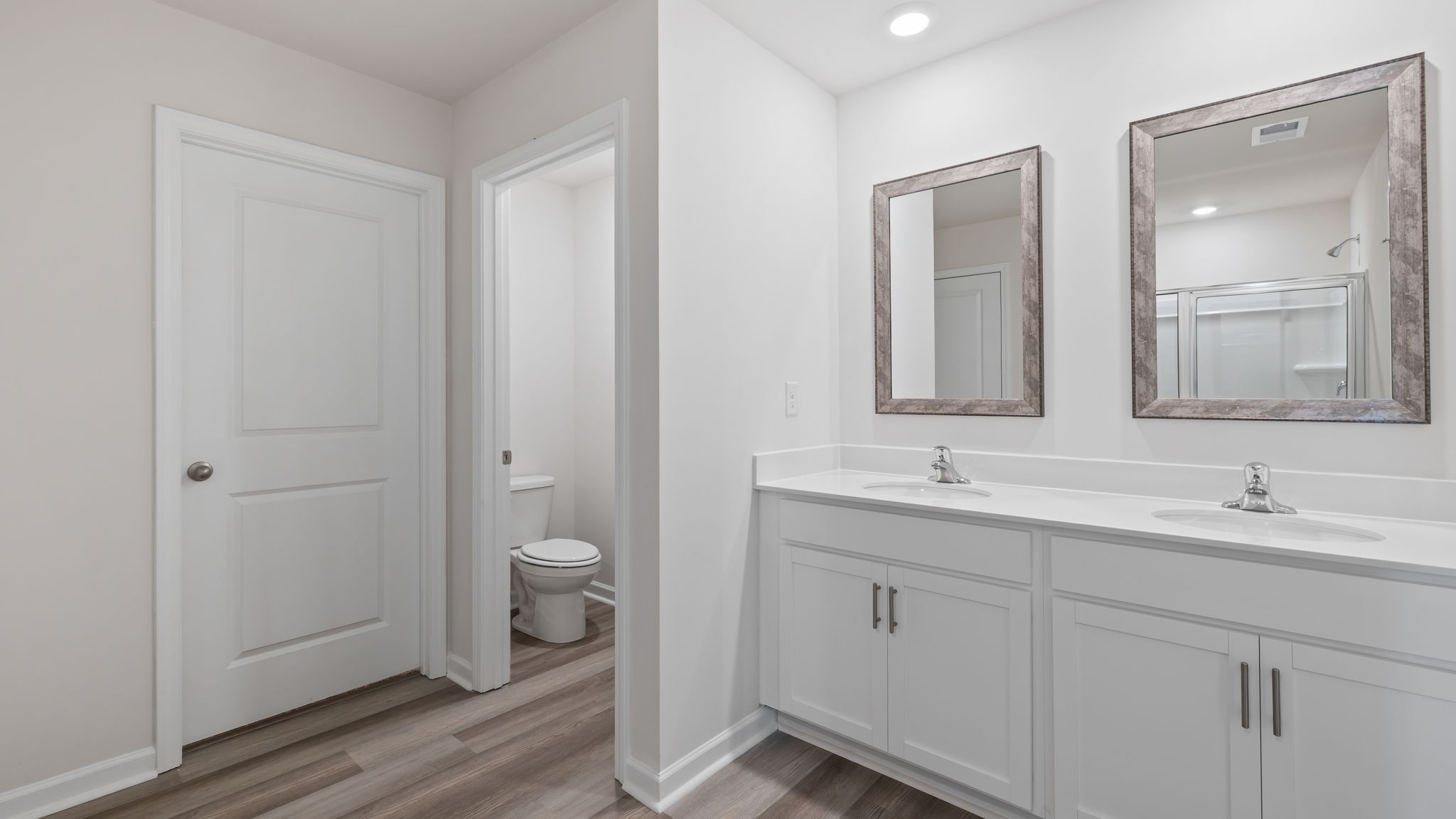 Primary bathroom with dual sink vanity and mirrors.