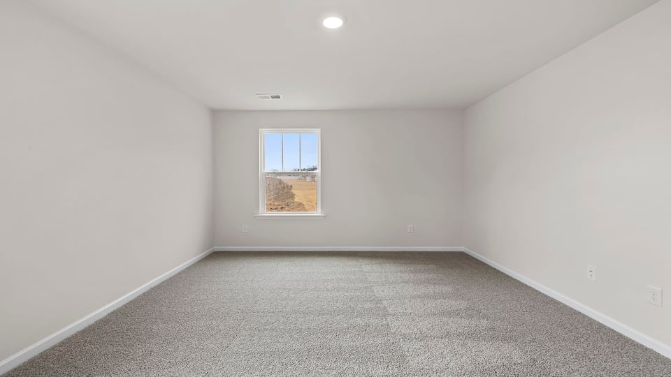 Primary bedroom with carpet and window.