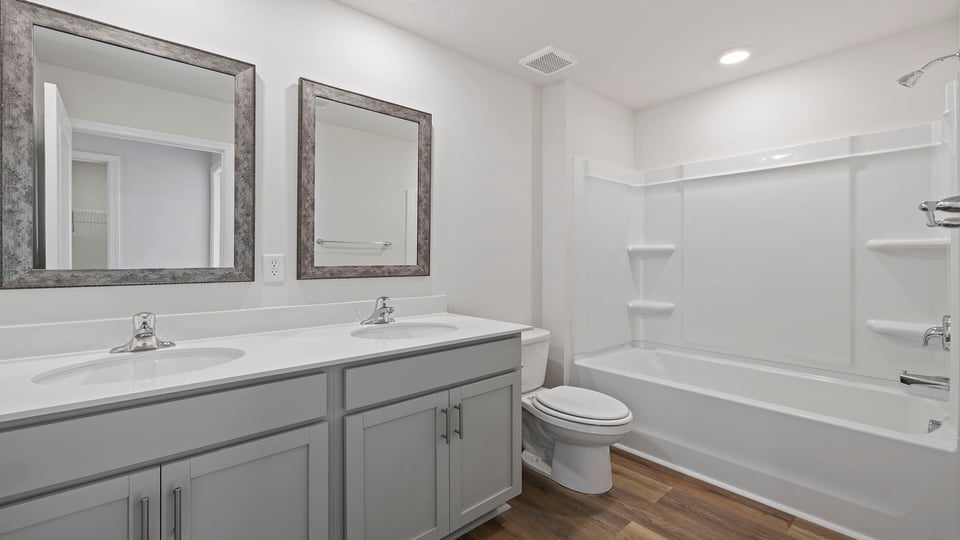 Hall bathroom with dual sink vanity and combination shower / tub.