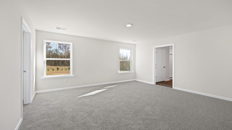 Primary bedroom with two large windows and carpet.