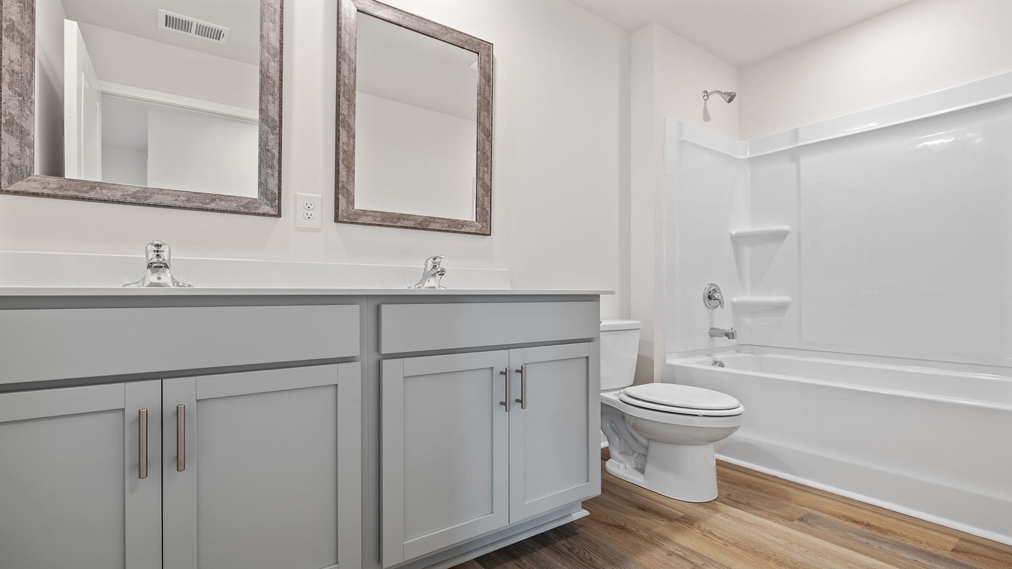 Hall bathroom with dual sink vanity and combination shower / tub.