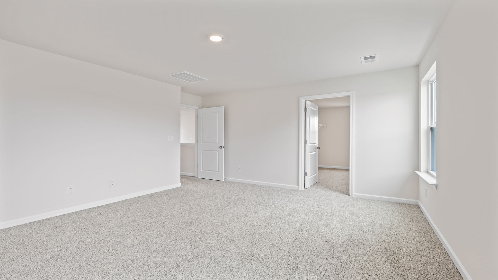 Primary bedroom with window, recessed lighting and carpet.