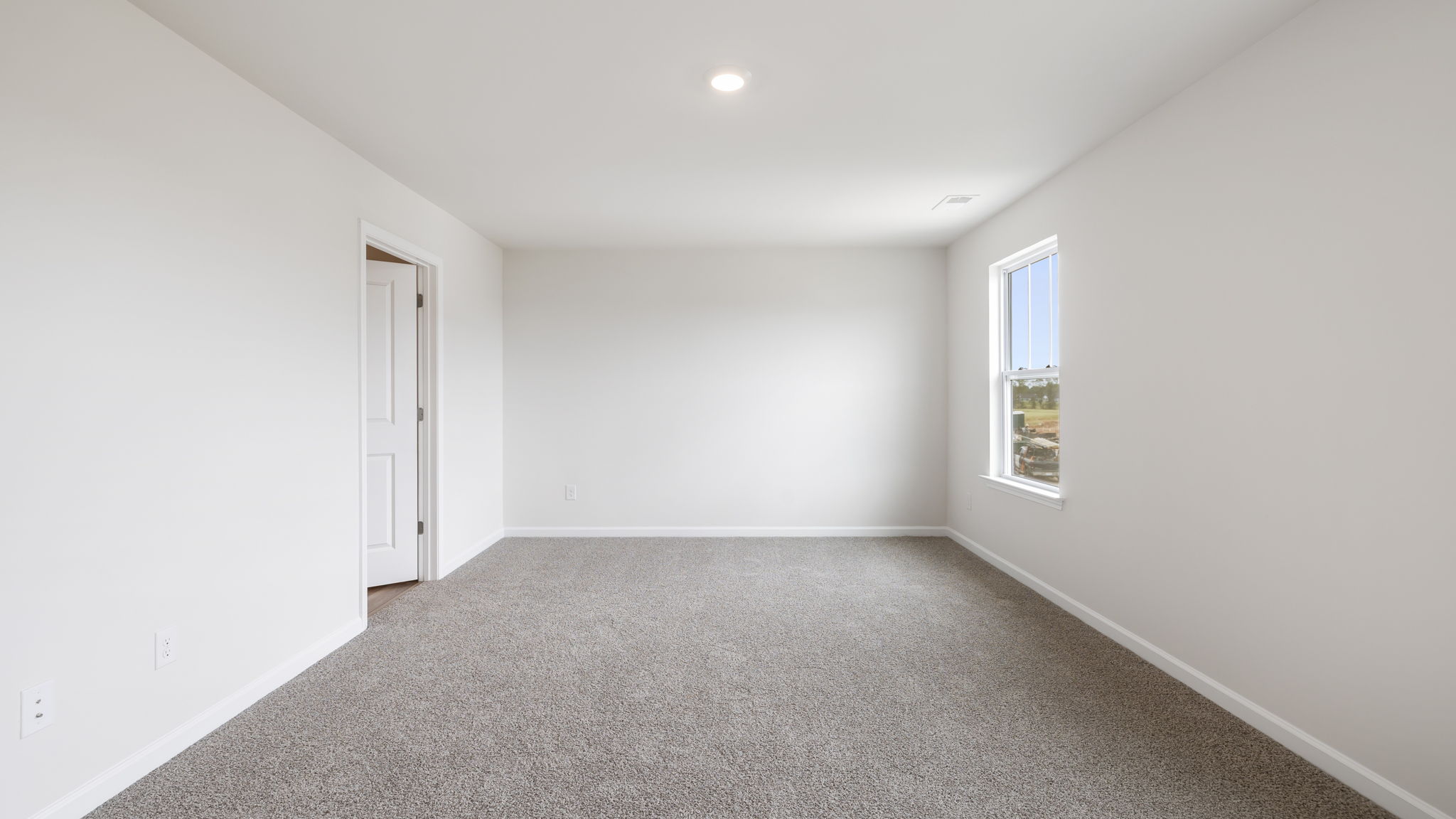 Primary bedroom with carpet and windows.