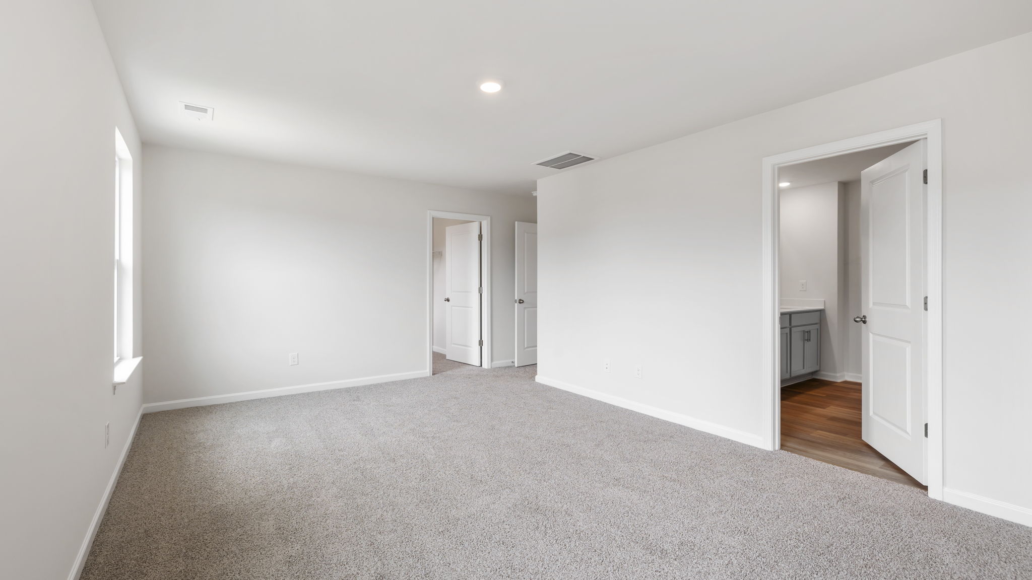 Primary bedroom with carpet and windows.