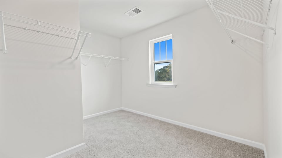 Primary bedroom with carpet and windows.