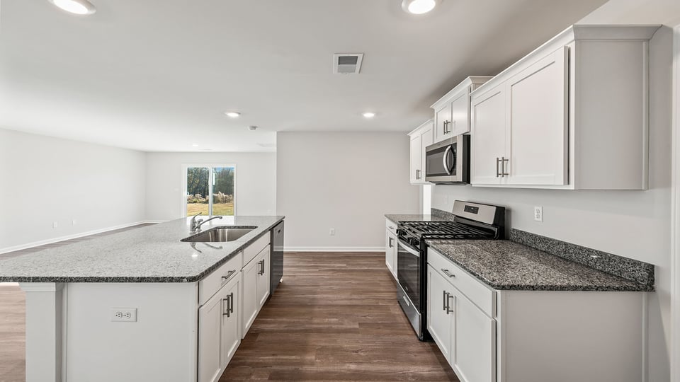 Kitchen island with quartz countertop hosts the sink and the dishwasher.