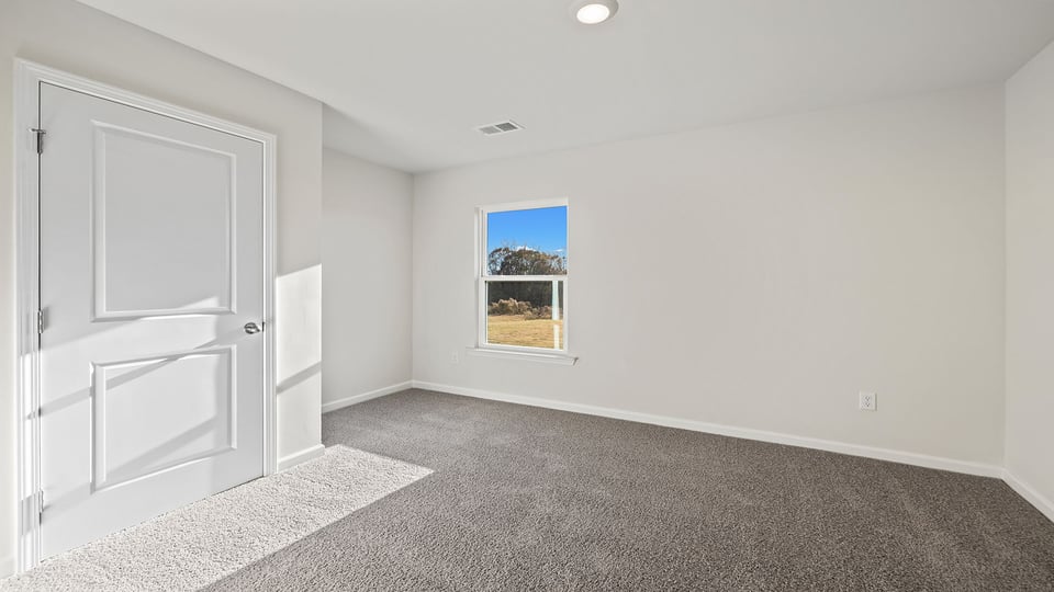 Bedroom on main level with carpet and window.