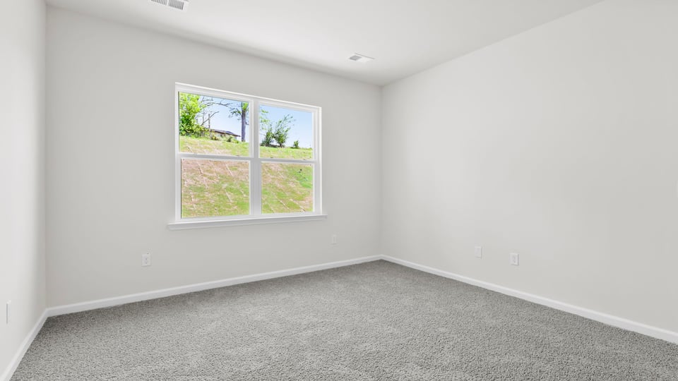 Primary bedroom with carpet and window.
