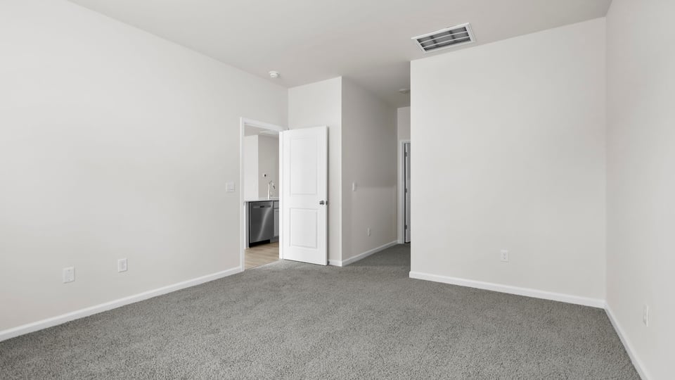 Primary bedroom with carpet and window.