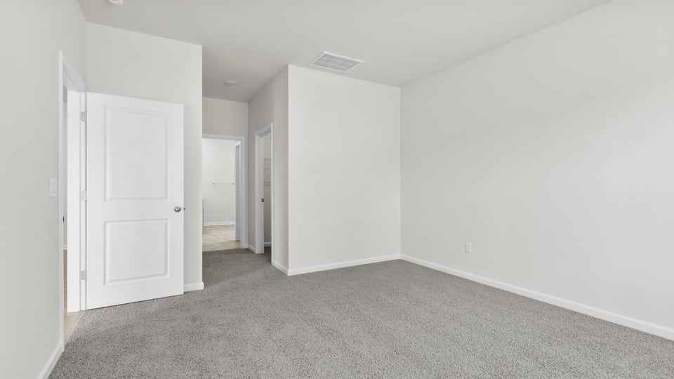 Primary bedroom with carpet and window.