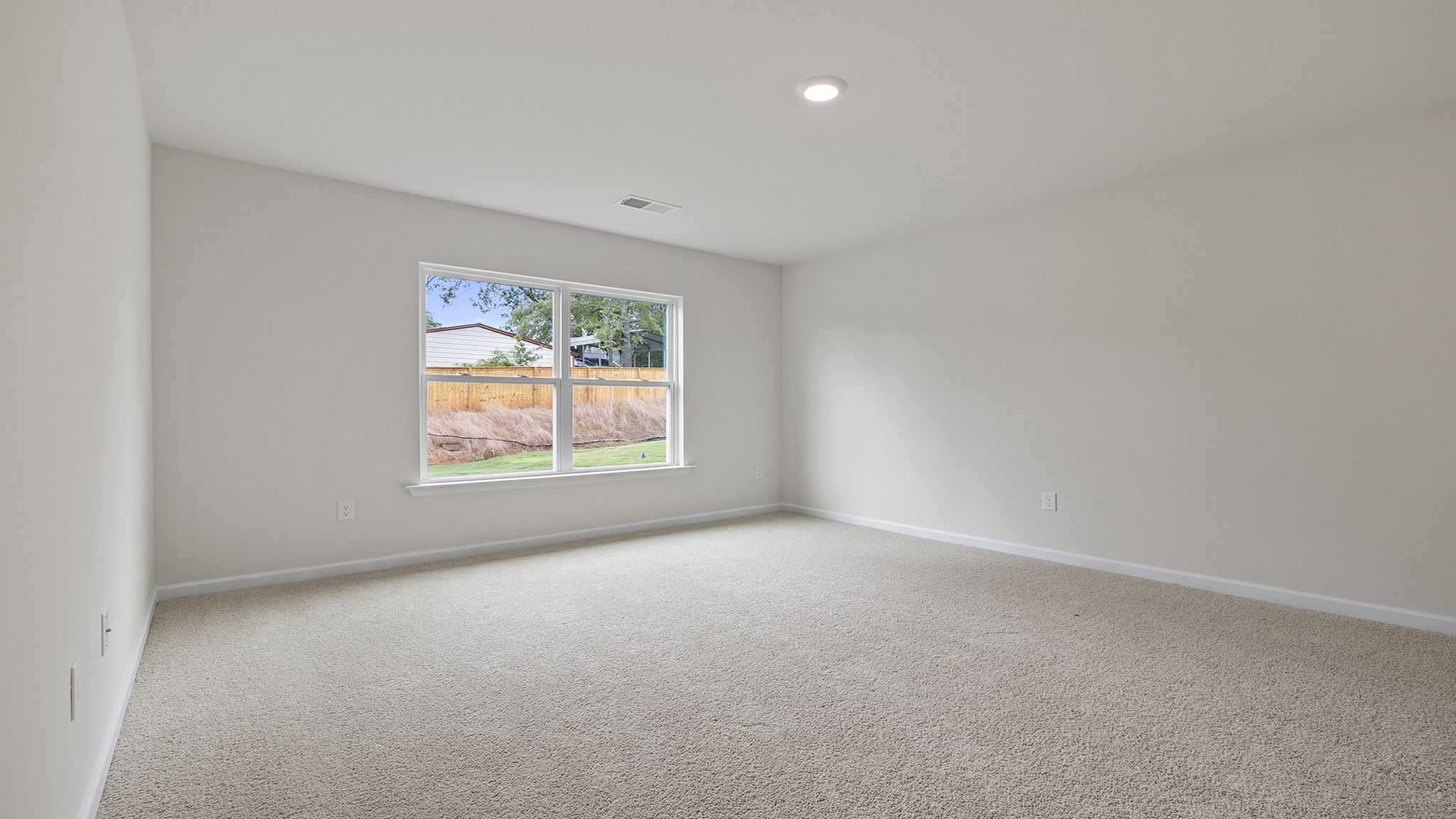 Primary bedroom with carpet and window.