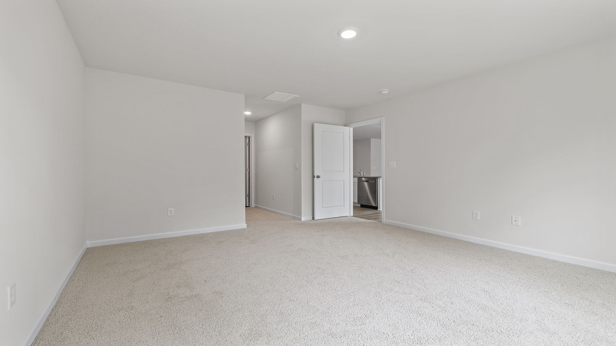 Primary bedroom with carpet and window.