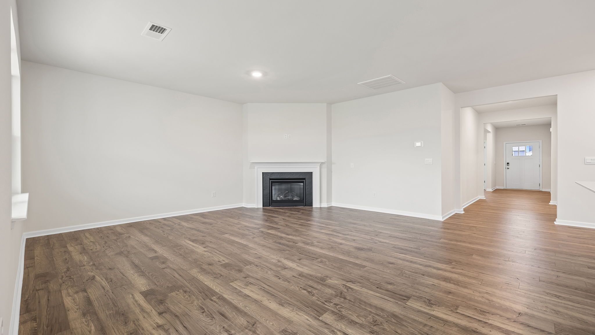View of family room with gas log fireplace and hallway to the entrance.