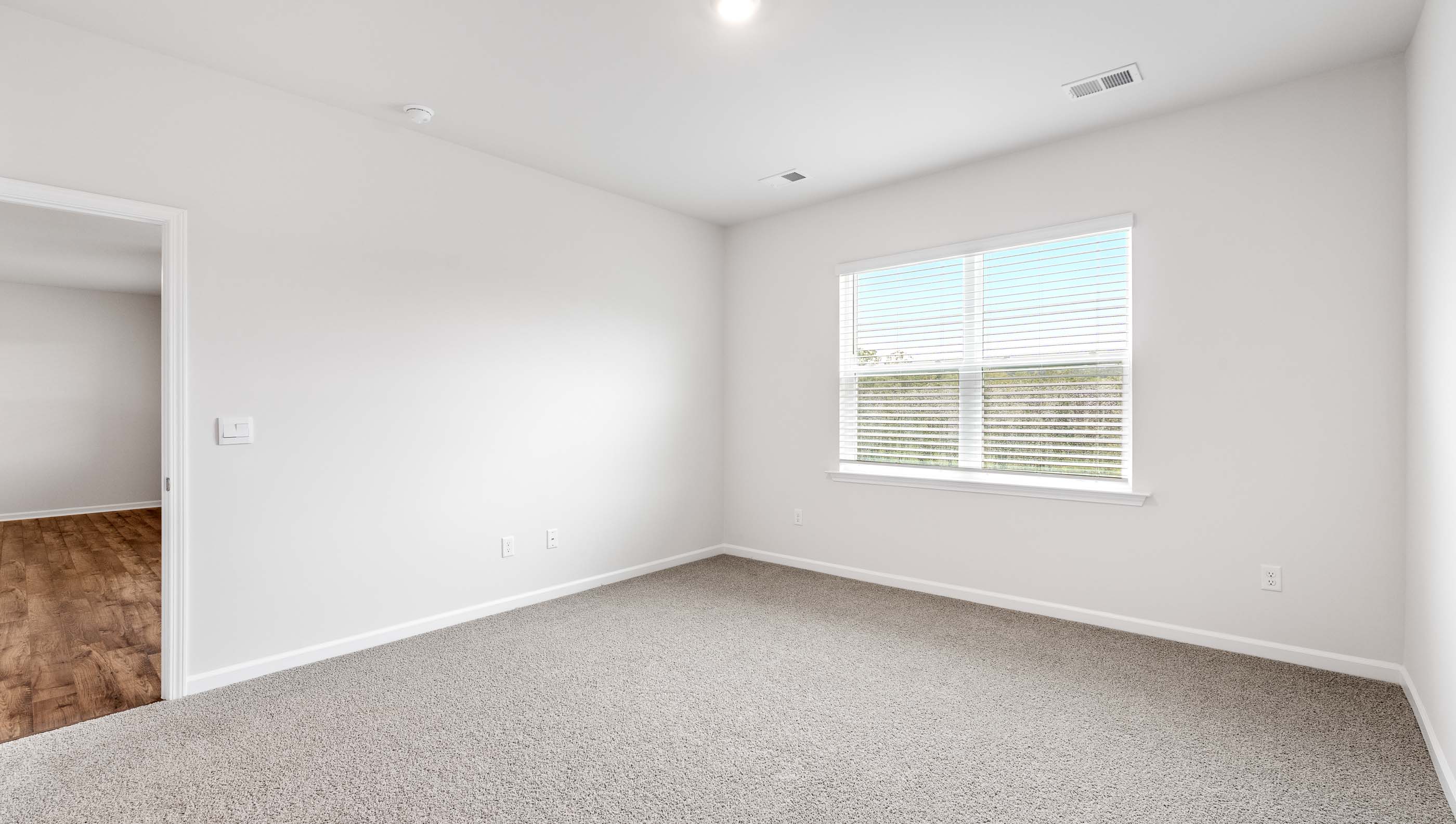 Primary bedroom with large window and carpet.