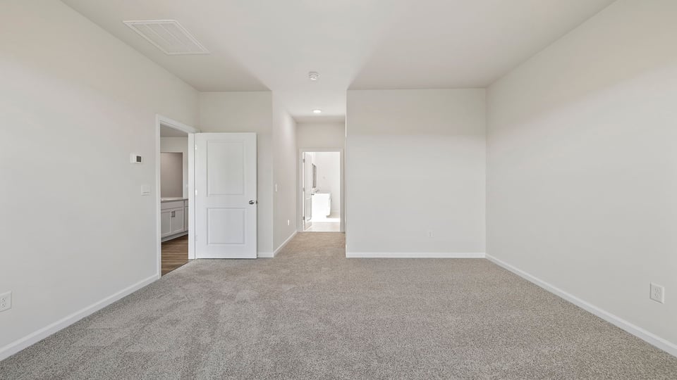 Primary bedroom with carpet and window.